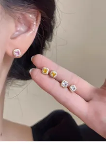Detailed view of square halo stud earrings with pink, yellow and white gemstones