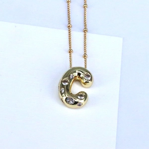 Detail view of 18k gold bubble letter C pendant necklace with sparkling zircon inlay