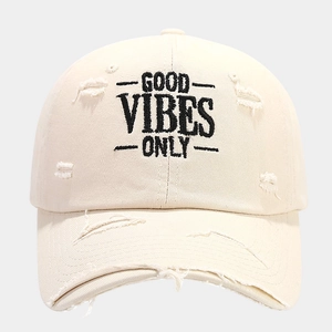 Close-up of distressed cream cotton baseball cap with Good Vibes Only embroidery
