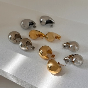 Dettaglio macro di orecchini a goccia lucidi in oro e argento con finitura a specchio