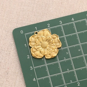 Macro shot of gold stainless steel flower pendant on cutting mat for size measurement