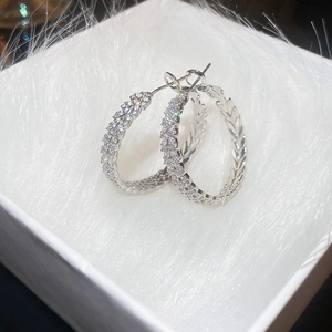 Macro shot of silver-tone hoop earrings with pave-set cubic zirconia on white fur