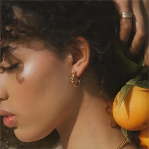 Close-up of model wearing 18K gold-plated twisted C-shaped earrings and matching jewelry