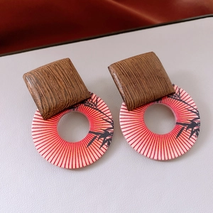 Detail of wooden geometric earrings with square studs and bamboo print round pendants