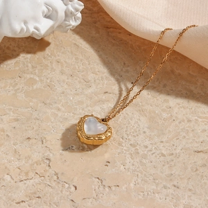 Detail view of a vintage gold heart pendant necklace with shell inlay on silk fabric