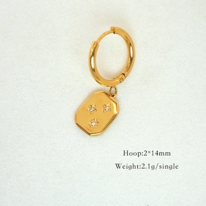 Detail view of 14K gold hoop earring with star-engraved pendant and small rhinestones