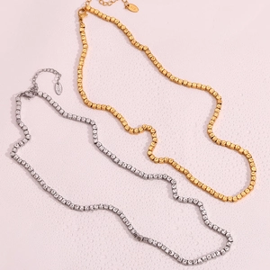 Close-up of gold and silver square bead necklaces with textured links on purple background