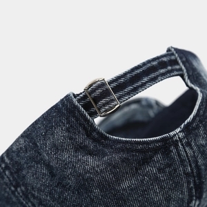 Dettaglio della fibbia in metallo regolabile e della trama denim di un berretto da baseball