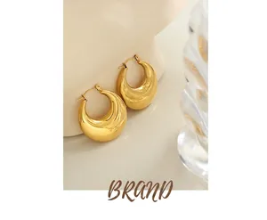 Detailed view of polished gold U-shaped earrings displayed on a white plaster statue