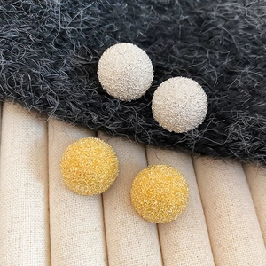 Detailed macro view of matte frosted gold and silver spherical stud earrings set