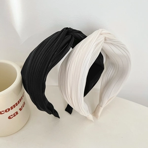 Detail view of black and white pleated fabric headbands with elegant knotted design