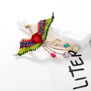 Close-up of vintage phoenix brooch featuring colorful enamel wings and red heart zircon