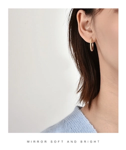 Detail of gold-plated spiral hoop earring on model showing elegant twisted texture