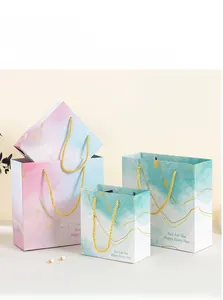 Detail view of pink and blue gradient gift bags with gold star patterns and rope handles