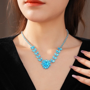Close-up of heart-shaped blue gemstone pendant and leaf design on silver necklace