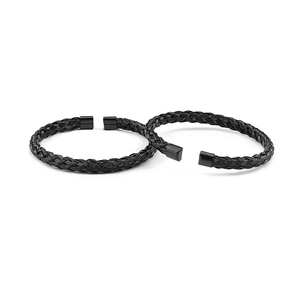Close-up of two black braided stainless steel wire open bracelets in punk style