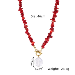 Detail view of red stone beaded necklace with baroque pearl pendant and gold toggle clasp