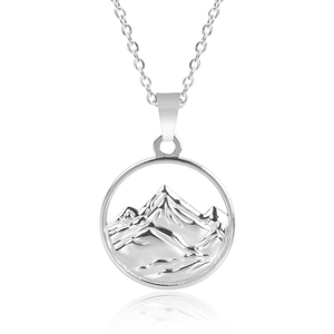 Macro shot of silver circular pendant featuring a hollow mountain silhouette on a fine chain