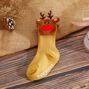 Detail of ginger rib-knit baby socks with a 3D plush reindeer on wooden background