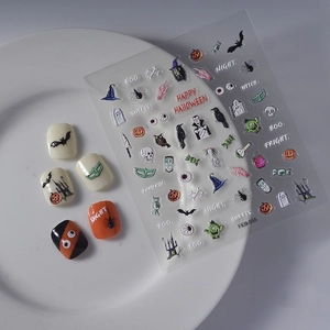 Halloween nail stickers with pumpkins and bats on a white plate for festive manicure art