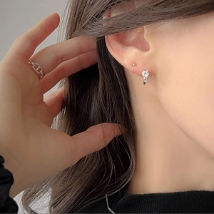 Close-up of a model wearing silver zircon hoop earrings and a chain link ring