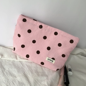 Pink corduroy makeup bag with black polka dots and white brand label on fabric