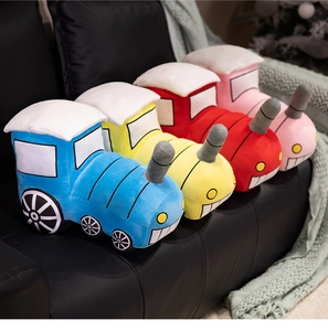 Detail of plush steam train pillows in vibrant colors on a black leather sofa