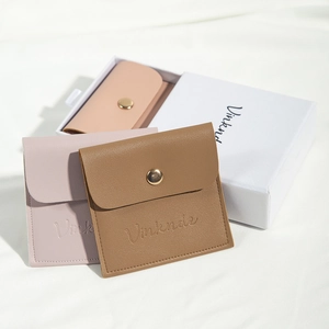 Detailed view of PU leather jewelry pouches in pink, purple, and brown with snap buttons