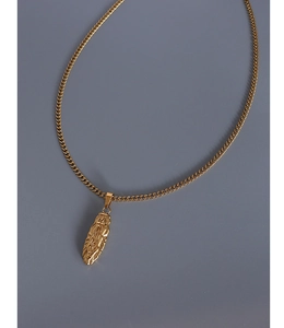 Close-up of golden oval medallion necklace with detailed queen portrait engraving