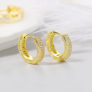 Macro shot of gold plated huggie hoop earrings with multi-row micro paved cubic zirconia