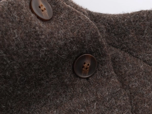 Détail macro du tissu en laine marron foncé avec boutons en résine sur le manteau