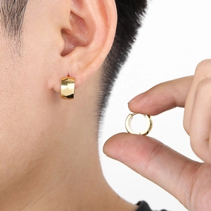 Detail shot of 7mm polished gold titanium hoop earring worn and held for scale