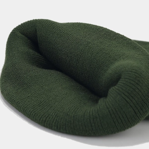 Detailed close-up of dark green ribbed knit beanie showing fine wool texture and stitching