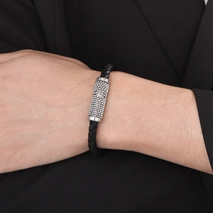 Close-up of men's black braided leather bracelet with silver pavé-set bead on wrist