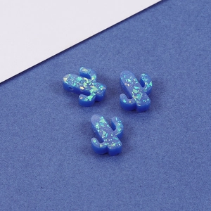 Three blue opal cactus pendants with iridescent sparkles on a split color background