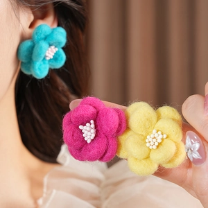Détail de boucles d'oreilles fleurs en feutre faites main en bleu, rose et jaune