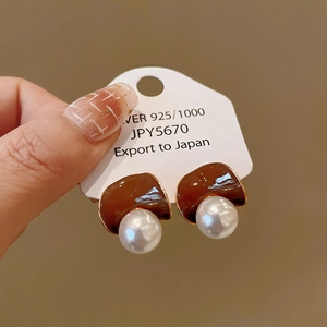 Gros plan sur des boucles d'oreilles en argent 925 avec perles blanches et émail marron