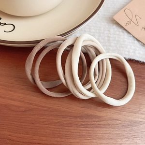 Set of five earth-toned high elastic hair ties displayed on a rustic wooden desk surface
