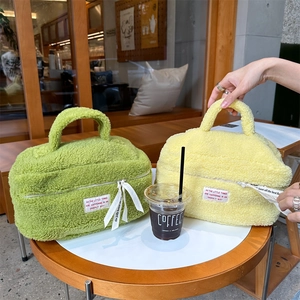 Detailed view of plush fuzzy cosmetic bags in green and yellow on a cafe table