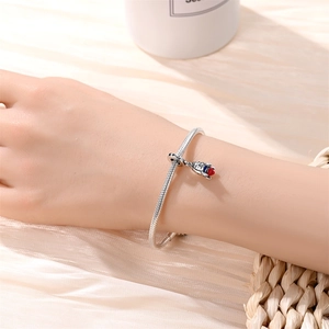 Detail of silver snake chain bracelet featuring a rocket charm on a model wrist