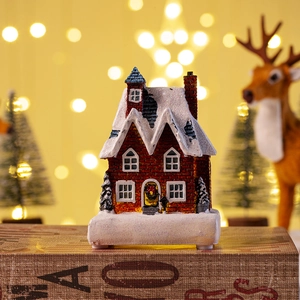 Detailed view of miniature Christmas cottage with warm LED light on snow-covered roof