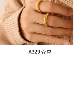 Close-up of gold croissant twist rings worn by model on a beige knit background