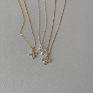 Detailed view of silver, gold, and rose gold cross necklaces with square-cut zirconia