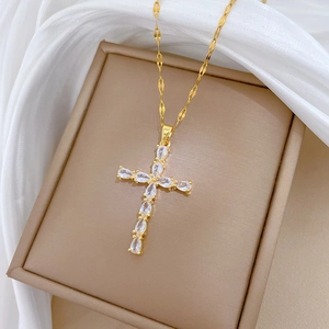 Close-up of golden titanium necklace with cross pendant featuring teardrop zircon stones
