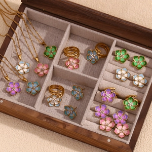 Detail of floral enamel jewelry set with pearls in a wooden box with beige linen lining