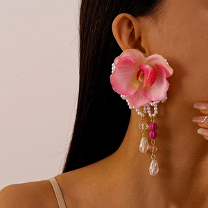 Detail of pink fabric orchid earrings with faux pearls and crystals on a model