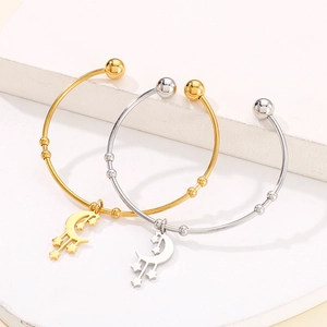 Modern moon and star pendants on gold and silver open bangles over white stone