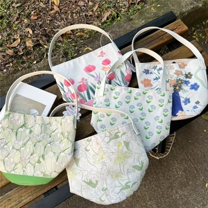 Floral canvas bucket tote bag with tulip patterns displayed on an outdoor park bench