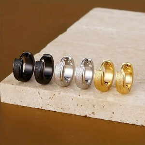 Macro shot of matte stainless steel hoop earrings in black, gold, and silver finishes