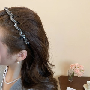Detail of elegant wavy crystal headband worn with pearl jewelry in a lifestyle setting